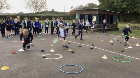 children taking it in turns to hit a beanbag into a hoop