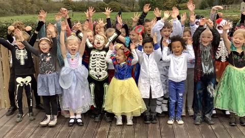 children in fancy dress, with their hands in the air, in a group photo