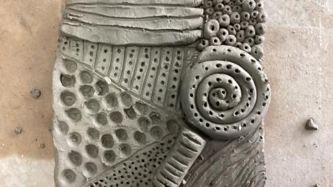 Another clay piece with spiral and dotted patterns.