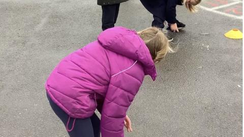 two children trying to pass a beanbag around their legs