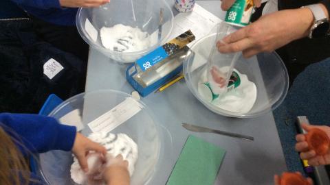 Children covering tomatoes in salt and bicarbonate of soda mixture