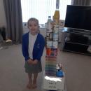 Girl next to tower built of household items 