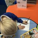 Child writing a penguin fact file